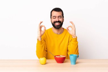 Beyaz bir adam zen pozunda kahvaltı yapıyor..