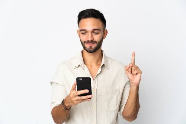 Beyaz arka planda cep telefonu ve parmak kaldırarak izole genç beyaz adam