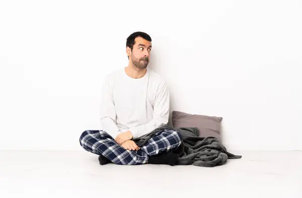 Blanke Man Pyjama Zittend Vloer Bij Binnenshuis Met Twijfels Terwijl Stockafbeelding