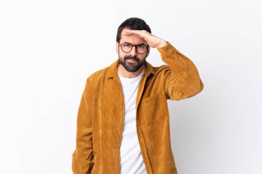 Beyaz arka planda kadife ceket giyen beyaz saçlı, sakallı yakışıklı bir adam bir şeye bakmak için uzaklara bakıyor.