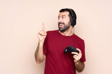 İzole edilmiş duvarın üzerinde video oyunu kontrolörüyle oynayan bir adam çözümü fark etmek için parmağını kaldırıyor.