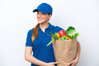 Genç teslimatçı kadın beyaz arka planda izole edilmiş bir paket yiyecek alıyor.