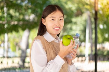 Dışarıdaki güzel Çinli kadın bir elma ve bir şişe suyla.