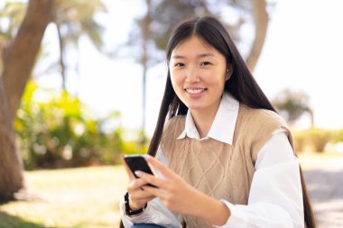 Dışarıdaki güzel Çinli kadın cep telefonu kullanıyor.