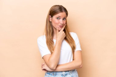 Beyaz tenli genç bir kadın bej arka planda izole edilmiş mutlu ve gülümsüyor.