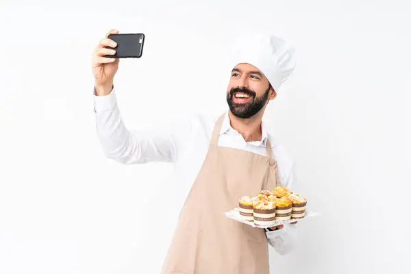 孤立した白い背景の上にマフィンケーキを保持している若い男は 自分撮りをする — ストック写真