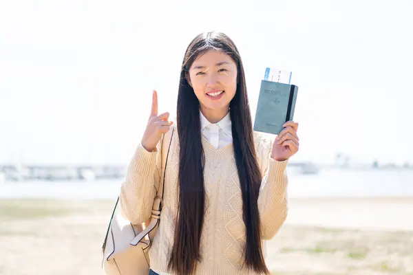 Young Chinese Woman Holding Passport Outdoors Pointing Great Idea 로열티 프리 스톡 이미지
