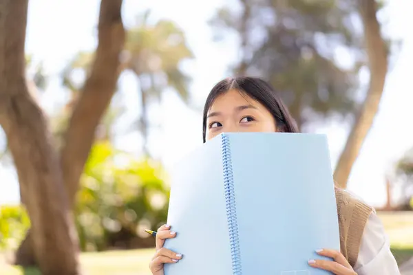 Pretty Chinese Woman Outdoors Holding Notebook Stock Photo