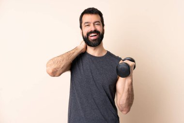 Beyaz sakallı sporcu arka planda halter kaldırarak gülüyor.