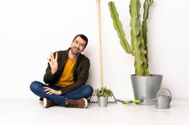 Bahçıvan içeride yerde oturmuş mutlu mesut parmaklarıyla dört tane sayıyor.