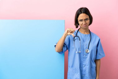 Soyutlanmış arka planda büyük bir pankartıyla genç melez bir cerrah kadın olumsuz bir ifadeyle baş parmağını aşağı gösteriyor.