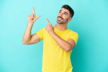 Mavi arka planda izole edilmiş genç beyaz adam işaret parmağıyla işaret etmek harika bir fikir.