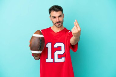 Genç beyaz adam rugby oynuyor. Mavi arka planda izole edilmiş. Gelen jest yapıyor.