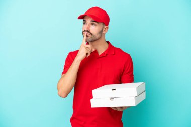 Teslimat yapan beyaz bir adam mavi arka planda izole edilmiş pizza kutularını topluyor.