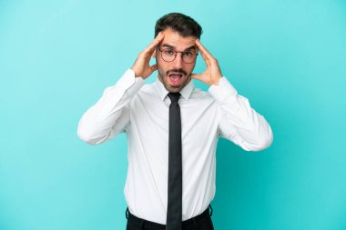 Beyaz iş adamı mavi arka planda izole edilmiş, sürpriz bir ifadeyle.