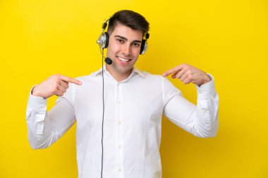Tele pazarlamacı beyaz adam sarı arka planda izole edilmiş kulaklıkla çalışıyor gururlu ve kendini beğenmiş.