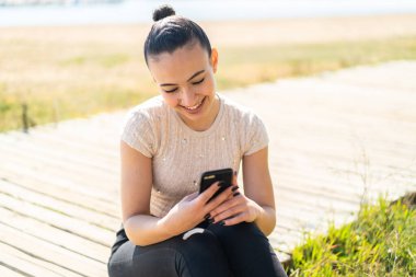 Dışarıdaki Faslı genç kız cep telefonuyla mesaj ya da e-posta yolluyor.