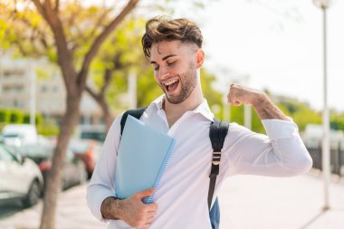 Genç yakışıklı öğrenci dışarıda zaferi kutluyor.