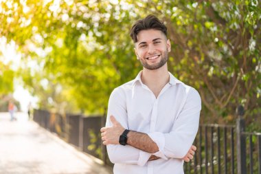 Dışarıdaki yakışıklı genç adam kollarını ön cephede çapraz tutuyor.