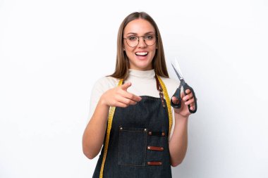 Beyaz arka planda izole edilmiş genç terzi kadın şaşırmış ve ön tarafı işaret ediyor.