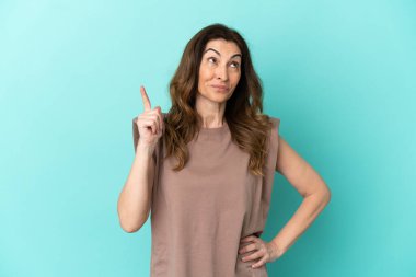 Orta yaşlı, beyaz bir kadın, mavi arka planda izole edilmiş.