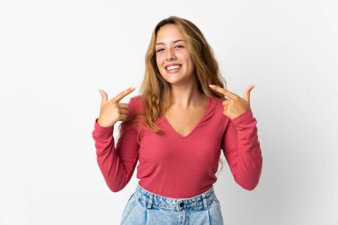 Mavi arka planda izole edilmiş genç sarışın bir kadın baş parmak işareti yapıyor.