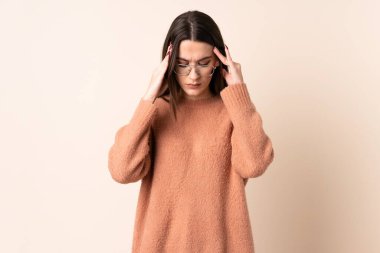 Soyutlanmış bej arka planda baş ağrısı olan genç bir kadın.