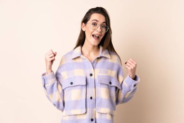 Tecrit edilmiş bej rengi arka planda genç bir kadın galibiyeti kutluyor.