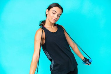 Mavi arka planda, atlama ipiyle izole edilmiş genç beyaz kadın.