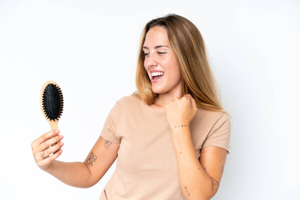 Молодая белая женщина с расчёской на белом фоне празднует победу