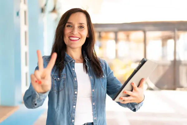 Mujer Mediana Edad Sosteniendo Una Tableta Aire Libre Sonriendo Mostrando Imagen De Stock