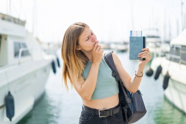 Dışarıda pasaportu olan genç sarışın bir kadın. Şaşırmış ve şok olmuş bir yüz ifadesi var.