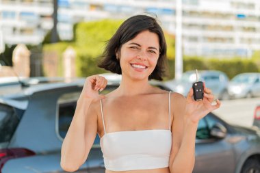 Genç, güzel bir Bulgar kadın arabanın anahtarlarını açık havada tutarken gururlu ve kendinden memnun.