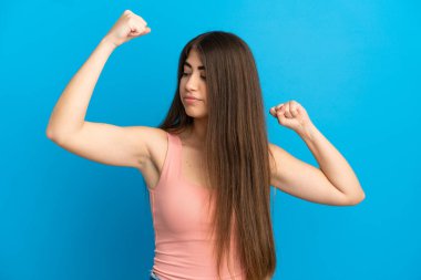 Mavi arka planda izole edilmiş beyaz bir kadın güçlü bir jest yapıyor.