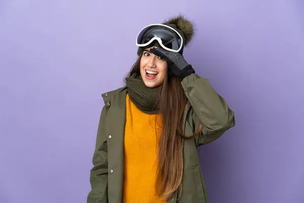 滑雪者用紫色背景隔离的雪板眼镜向旁边看的时候 做了一个令人惊讶的手势 — 图库照片