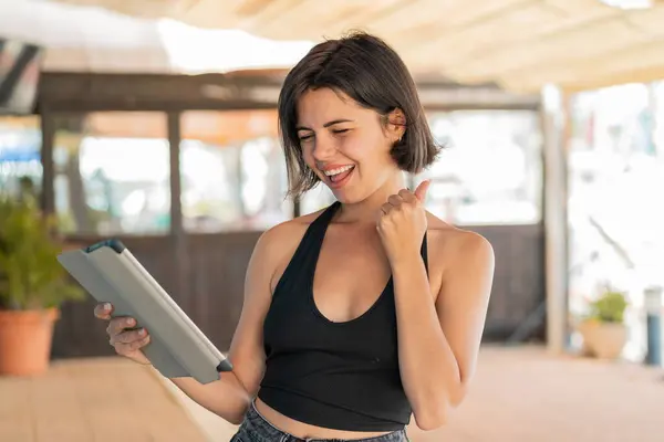 Young Pretty Bulgarian Woman Holding Tablet Outdoors Celebrating Victory Royalty Free Stock Photos