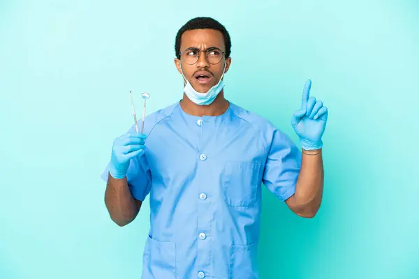 Dentista Afroamericano Sosteniendo Herramientas Sobre Fondo Azul Aislado Pensando Una — Foto de Stock
