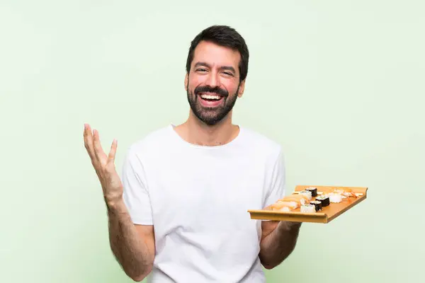 Ung Stilig Man Med Sushi Över Isolerad Grön Vägg Ler Stockfoto