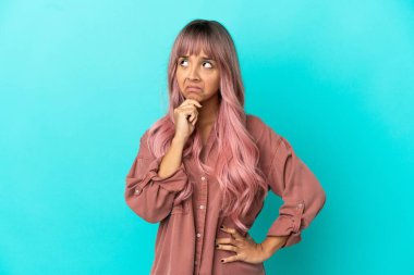 Mavi arka planda pembe saçlı, melez bir kadın. Şüpheleri var.