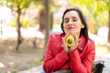Avokado tutan orta yaşlı bir kadın.