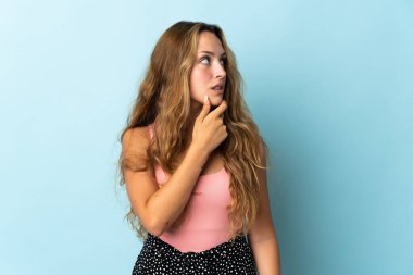 Mavi arka planda izole edilmiş genç sarışın kadının şüpheleri var.