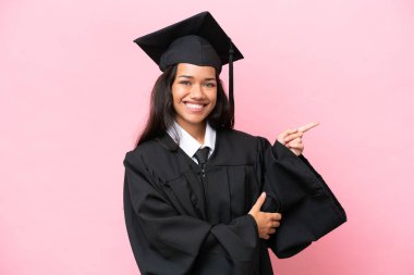 Üniversiteden mezun genç bir Kolombiyalı kadın pembe arka planda izole edilmiş.