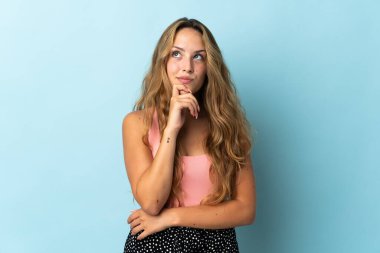 Genç sarışın kadın mavi arka planda izole edilmiş ve yukarı bakıyor.