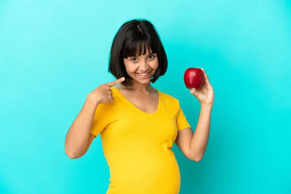 青い背景に孤立したリンゴを保持している妊娠中の女性は 親指を上げるジェスチャーを与えます — ストック写真