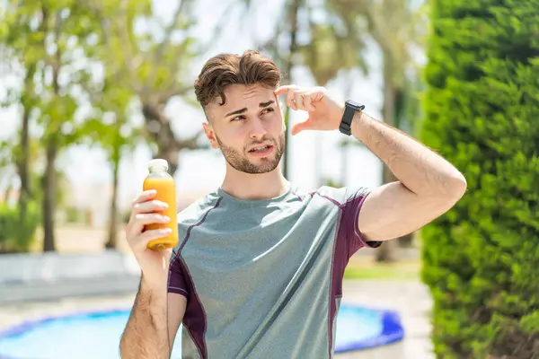 Young Handsome Sport Man Holding Orange Juice Outdoors Having Doubts Stock Picture