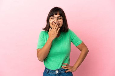 Genç melez bir kadın pembe arka planda izole edilmiş mutlu ve gülümseyen bir ağızla eli kapalı.