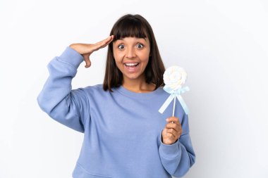 Beyaz arka planda lolipop tutan genç bir ırk kadını sürpriz bir ifadeyle izole edilmiş.