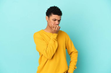 Genç Afrikalı Amerikalı bir adam mavi arka planda izole edilmiş.