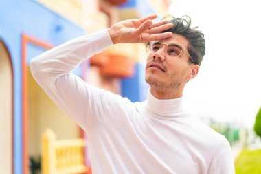 Dışarıda gözlüklü ve yorgun beyaz bir adam var.