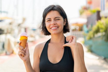 Açık havada kornet dondurması olan genç ve güzel Bulgar kadın gururlu ve kendinden memnun.